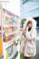 A woman standing in front of a vending machine.