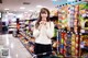 A woman standing in front of a store filled with snacks.