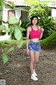 A woman in a pink top and denim shorts posing for a picture.