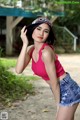 A woman in a pink top and denim shorts posing for a picture.