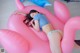 A woman laying on a pink flamingo shaped pool float.