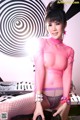 A woman in a pink top and fishnet stockings posing for a picture.