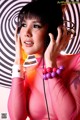 A woman in a pink dress holding a pair of headphones.