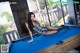 A woman in a blue dress is sitting on a pool table.