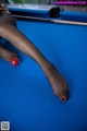 A woman is playing pool with a red ball.