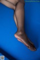 A woman's legs in black stockings on a blue background.