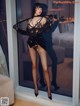 A woman in a black lingerie posing in front of a window.