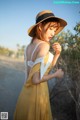 A woman in a yellow dress and a straw hat.