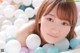 A young woman laying in a ball pit filled with white and blue balls.