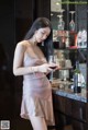 A woman standing in front of a bar holding a glass of wine.