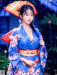 A woman in a blue kimono holding an orange umbrella.