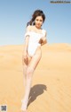 A woman in a white bathing suit standing in the desert.